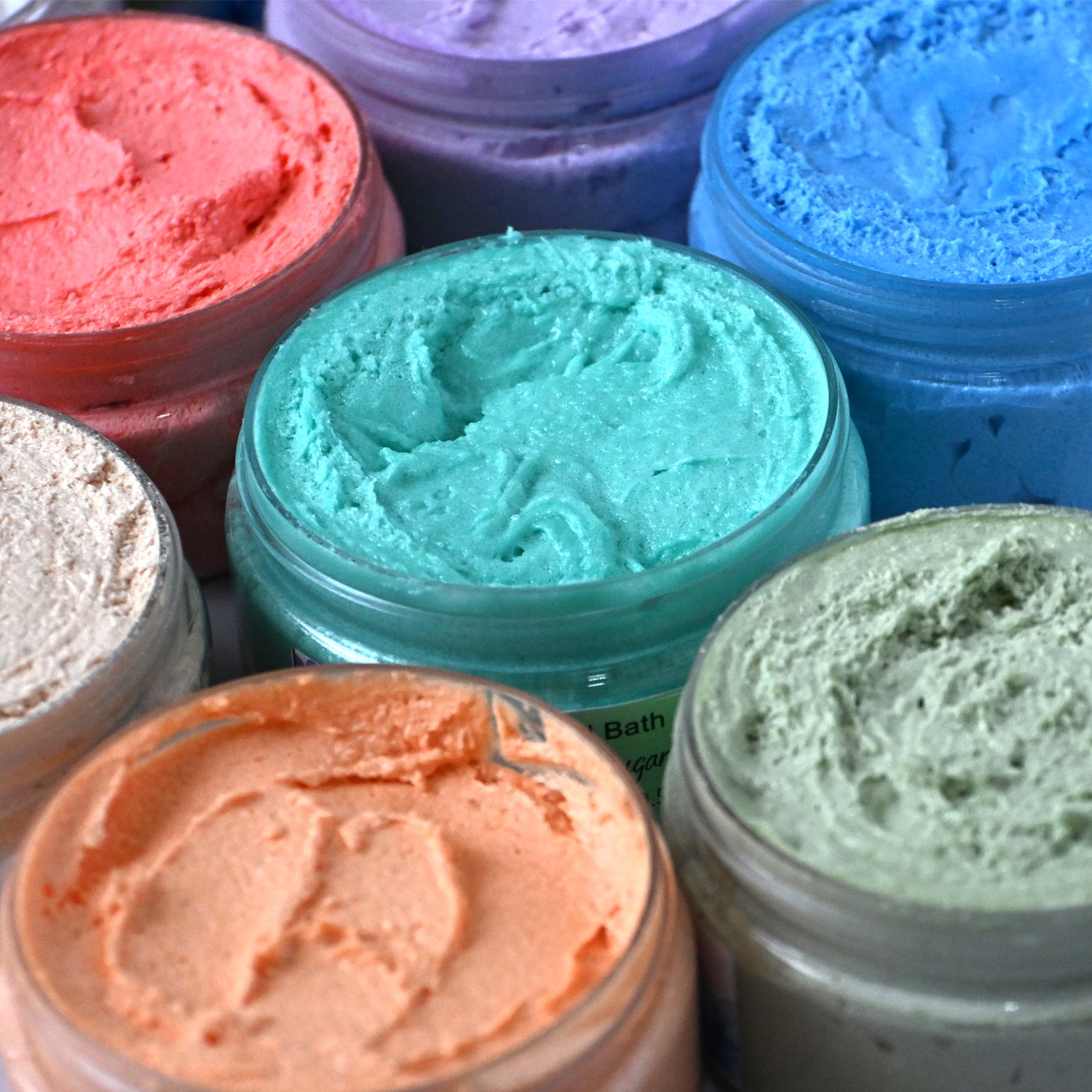 Assorted colored jars of whipped sugar scrub.
